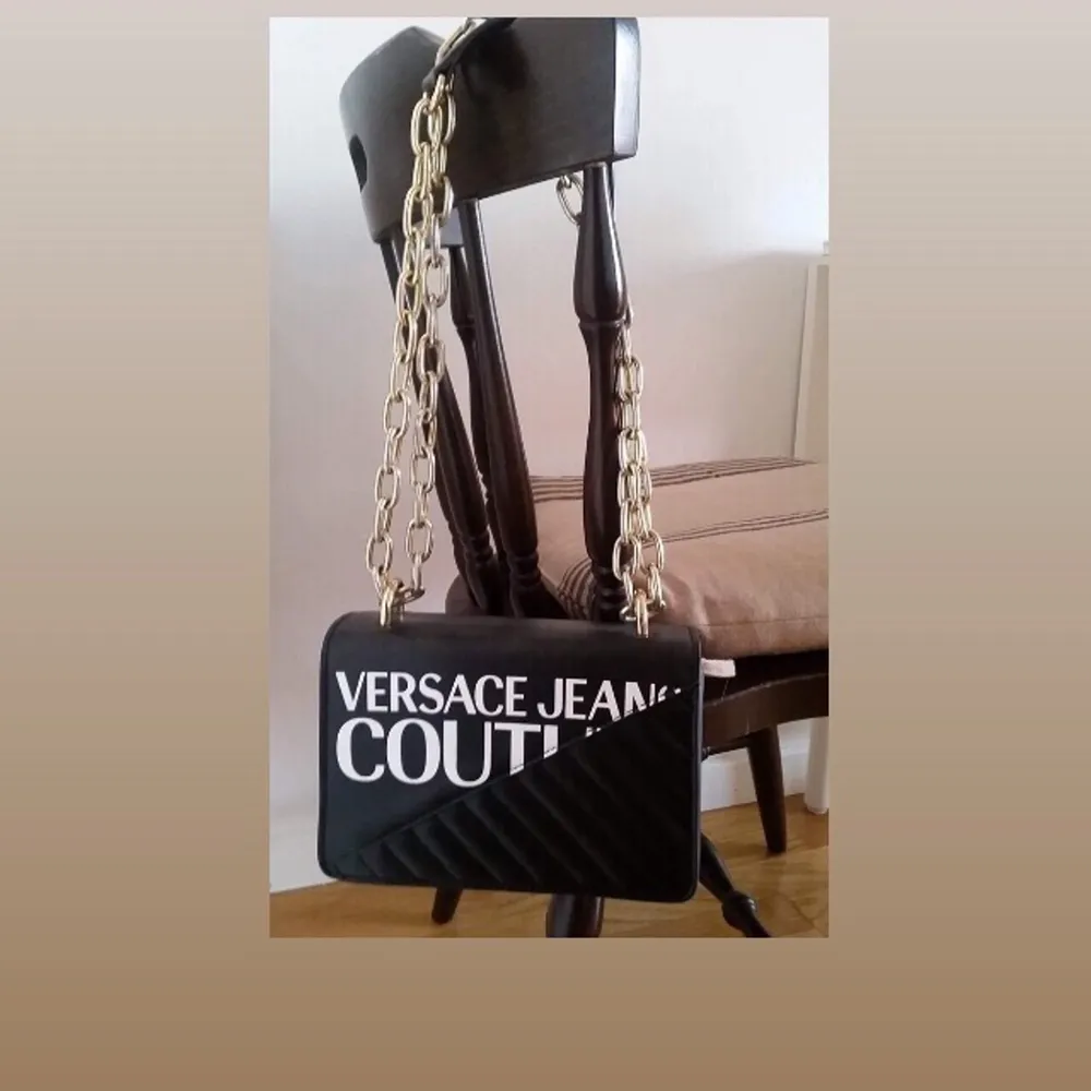 En originell Versace Jeans Couture axelremsväska med tryck och guldkedja. Väskan var en gåva och är oanvänd. Höjd: 14cm Längd: 20cm Vidd: 6 cm.. Accessoarer.