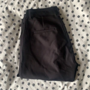 Kostymbyxor  - Svarta kostymbyxor från BIKBOK, tighta över lår och midja. Flate nedtill.