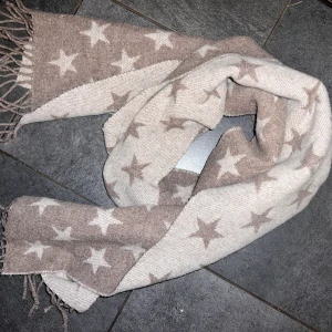 Gant halsduk - Varm skön halsduk från Gant med stjärnor, ena sidan är mörkbeige med ljusa stjärna och andra sidan ljus beige med mörka stjärnor. Nypris ca 750kr Fraktkostnad tillkommer på ca 50kr