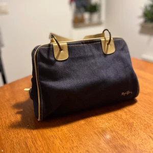 Handväska Björn Borg i jeanstyg - Handväska av märket Björn Borg i jeanstyg. Insidan har ett svart foder, ficka med dragkedja samt ett litet extrafack. Handtagen är ljust beigea.   MÅTT 21 cm hög 16 cm djup  30 cm bred