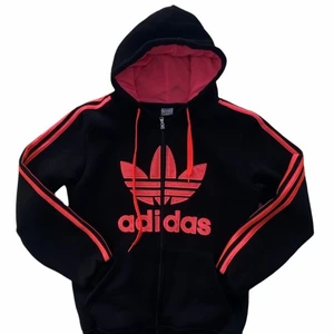 TJOCKTRÖJA ADIDAS - En svart tjocktröja med knallrosa tryck från Adidas, med dragkedja.