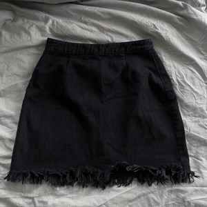 Jeanskjol med fransar - Svart kjol i jeans med fransar längst ner. Sjukt snygg men tyvärr blivit lite liten för mig. Storlek 36. 