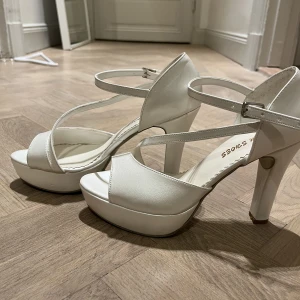 Vita klackskor strl 39 - Så fina klackskor i glansigt material, i den populära platform-modellen! Beställda online, men aldrig använda då de tyvärr inte passar mig😭 Perfekta till studenten, skolavslutningen eller bara under sommaren! 🤍😍