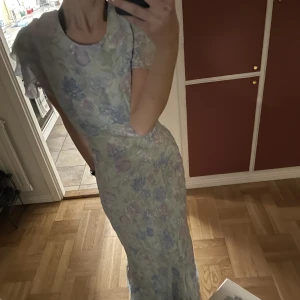 Långklänning  - Unik klänning, helt oanvänd. Så fin till midsommar. Vackra somriga färger. Öppen i ryggen och med dragkedja och knapp🌷Helt slutsåld, kan bli budgivning.