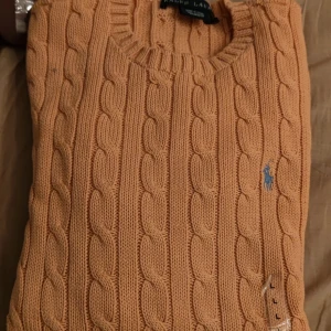 Ralph Lauren kabelstickad tröja Dam - Hej! Köpte denna fina kabelstickade tröjan i Usa i Ralph Lauren butiken. Det var dock fel storlek för oss. 100% Orginal. Helt ny,  aldrig använd.  Orange färg med Grön logga. 