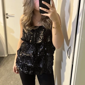 Svart glittrigt linne - Svart glittrigt linne med volanger, perfekt till nyår!!  Aldrig använd!