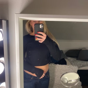 Svart topp från Nelly - Säljer min långärmade svarta topp i storlek S, köpt på Nelly. På sidorna finns det snörning och tröjan är i bra skick. Säljer den för 150 kr, köpare står för frakt!💕