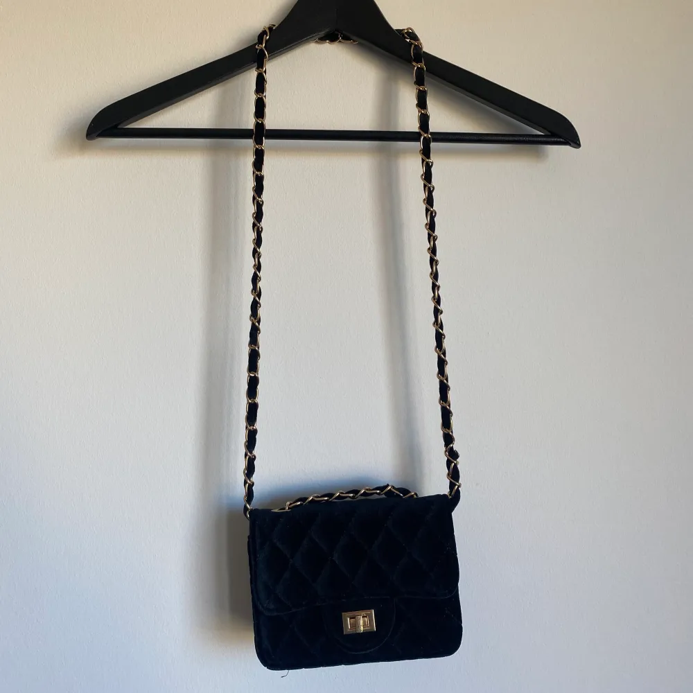 Snygg svart crossbody väska med guldfärgade detaljer. Lite nött på gulddetaljen på framsidan. . Väskor.