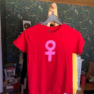 Röd T-shirt med rosa kvinnomärke. 35  kr plus frakt, kan hämtas i Borås 