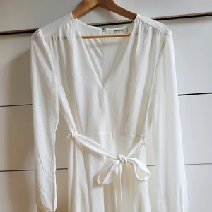 Vit långärmad klänning - En stilren vit klänning i storlek 38. Perfekt till studenten! Det finns ett band i midjan som går att ta av. Klänningen är oanvänd och köpt här på plick, lappen finns kvar. Priset är prutbart vid snabb och smidig affär. (Den andra bilden är lånad)