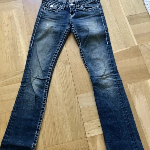 True Religion Jeans - Så snygga True Religion jeans med diamant detaljer. Lowrise med raka ben. Tyvärr har diamanterna lossnat på bakfickorna, men går att sätta på nya. Innerbenslängd: 77cm. Storlek: 24.