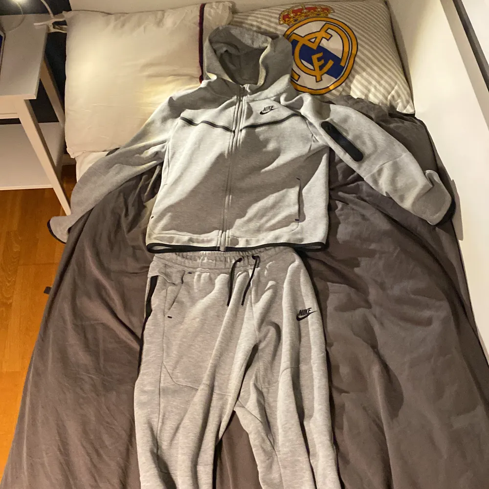 En grå Nike tech fleece som är i samma skick som en ny, inte en skråma.  Ord pris 1600 för byxor och koftan  Byxor: storlek L på barn Kofta: storlek L på barn. Hoodies.