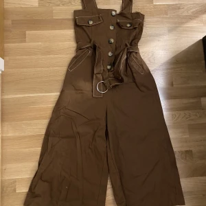 Jumpsuit - Brun jumpsuit/ byxdress. Aldrig använt. Lappen kvar. Vida ben. Storlek S/M