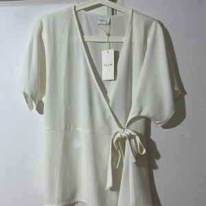 Vit topp med knytband - Vit topp med knytband. Inte använd men Liten fläck på backsidan vid nacken. Storlek 42. Ordpris: 379kr 