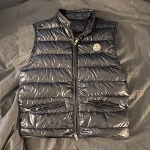 Moncler Gui Väst - Tjena, säljer denna Moncler Gui  storlek 2/S 7/10 i skick pga ett väldigt lite hål precis brevid dragkedjan och att den är lite använd. Annars är den i väldigt fint skick. Äkta såklart inget og men äktighetsbevis finns. Bud: 2200 Bin: 2800 Kan bytas 