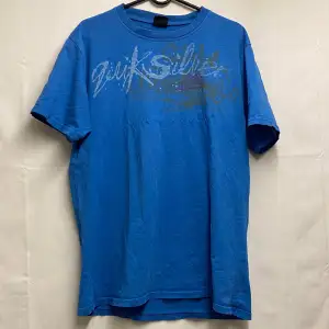 En blå quicksilver t-shirt i bra skick förutom att det är två väldigt små hål på framsidan av tröjan som man inte märker. 