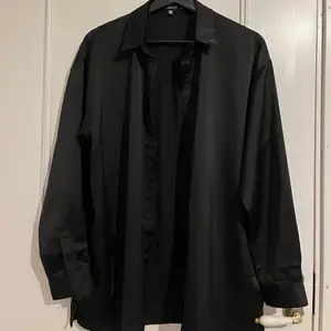 En svart skjorta i satin från boohoo i strl 34. Aldrig använd