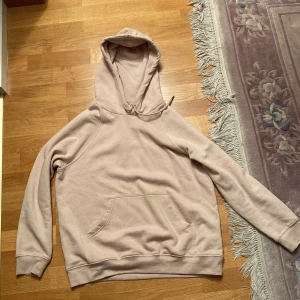 Ljus rosa hoodie från HM i storlek M - En ljusrosa hoodie i storlek M från HM. Använd ett fåtal gånger. Mjuk och härlig, perfekt till hösten! Ungefär 90cm lång. Ganska stretchig. Gjord av bomull och polyester!