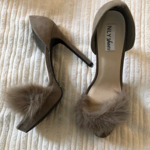 Högklackat med fuskpäls - Helt oanvända klackar, strlk 39 från NLY shoes. Älskar dessa högklackade skor, köpte en storlek större när de var dem sista kvar och hoppades på att de skulle passa. Men tyvärr är dem för stora för mig. Säljer dem därav. Skon är i grå färg och suede material med fuskpäls vid tårna. 