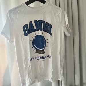 GANNI t-shirt - Säljer denna super coola tröja från Ganni. Den är i fint skick ❤️ kan gå ner i pris vid snabb affär. Finns några lätt ljusgula detaljer, de syns inte mycket, men försökte fota och ringa in dem!