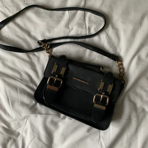 Cross-shoulder-bag från River Island - Skitsnygg svart axelväska i fakeläder som imiterar ormskinn. Gulddetaljer och långt axelband. Lite sliten i textilen och har även blivit lite tillplattad men det syns inte när den är full! 23x14 cm.