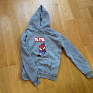 Spider man/Marvel hoodie - Oanvänd Marvel hoodie från Usa.  Storlek m (väldigt liten i storlek) Färg: grå.  Material: polyester Mått Axelmått: 47,5 cm Byst: 100 cm Armlängd: 57 cm Längd: 61 cm