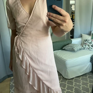 Rosa Midiklänning - Ljusrosa midiklänning från Vila som använts vid ett tillfälle. Knyts kring midjan och faller vackert mot kroppen. 