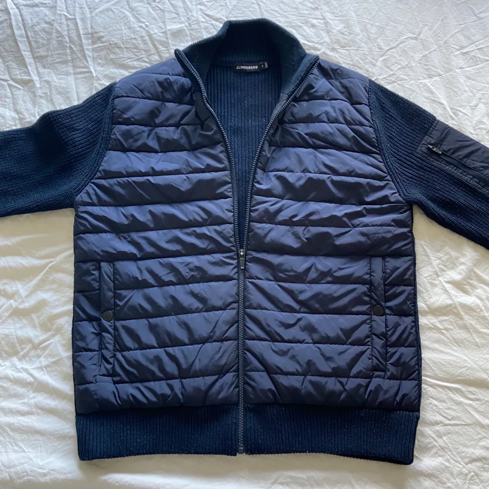 J Lindeberg Hybrid (cardigan) Jacket. Knappast använd men har legat i garderoben ett tag men är i bra skick, inga flaws eller liknande.  Storleken är medium, säljes för 999kr + porto. Jackor.