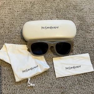 Yves Saint Laurent solglasögon - YSL solglasögon i en ljusbeige färg med små gulddetaljer på sidorna. Nypris är 2800 kr🤍🤍 Du får med allt på bilden! Glaset är mer ljusa än på bilden.