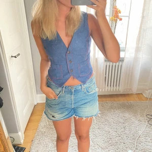 Jeansväst - En jeansväst köpt på beyondretro Andra bilden visar hur västen ser ut från början men jag gillar att vika ner den som på bild 1. Går att spänna åt i ryggen (bild 3)