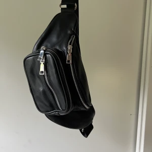 Väska - mycket fräsch och snygg väska. Väskan har 3 fack med dragkedja. Bandet runt går att justera och anpassa själv hur man vill spänna det. Mycket fint skick  