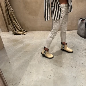 Kritstrecksrandiga kostymbyxor - Stretchiga svartvitrandiga byxor med fickor fram o kavajfickor bak., fint skick.