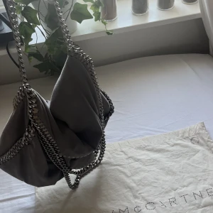 Stella McCartney - Säljer min superfina Stella McCartney väska då den inte kommer till användning längre. Väskan är i använt skick med lite missfärgade kedjor och en liten fläck som inte syns vid användning, skriv privat för fler bilder. Självklart äkta, dustbag medföljer!💕