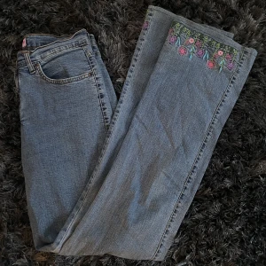 Y2k flare jeans broderi - Super fina jeans i stretchigt material med broderade blommor längst ner. Står ingen storlek men passar bra på mig som är 170 och har w26