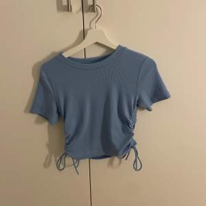Blå t-Shirt med snören som man kan knyta. Köpt på zara för 2 år sen men har aldig kommit till användning. Stl M