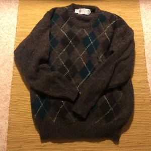Brun stickad tröja argyle - Snygg tröja i ull med argyle mönster. Storlek medium skulle jag säga. Ett litet hål på framsidan, går säker att laga men inget jag har tänkt på. Kan mötas i Lund eller Malmö annars betalar köpare frakt 