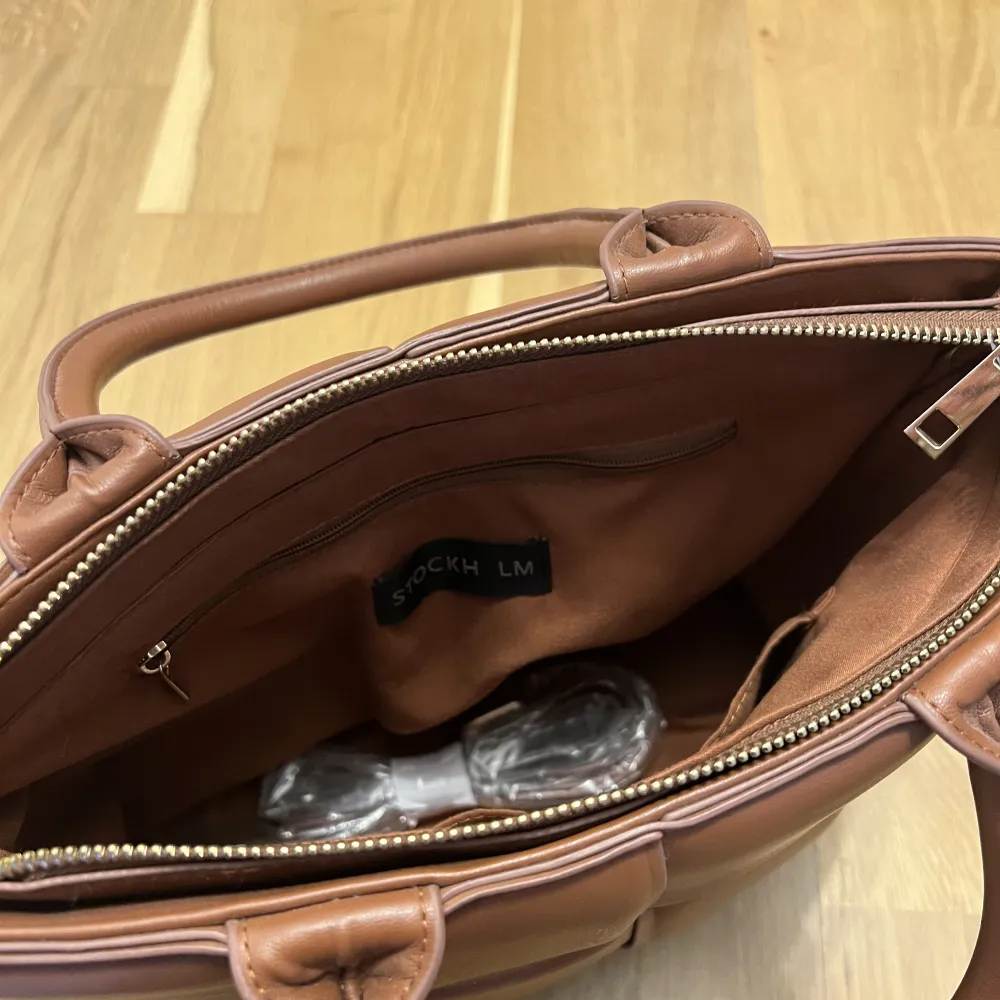 Brun handväska från märket ”Stockh lm”. Cirka 35x25 cm. Finns en längre rem.. Väskor.