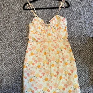 Mönstrad klänning NAKD - Mönstrad gullig klänning från NA-KD. Justerbara axelband och knytning därframme. Som ny, nästan oanvänd. Kort, strl Xs.