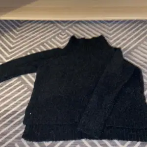 En stickad tröja med polohals från H&M. Slits på sidorna och några cm längre bak än fram. 