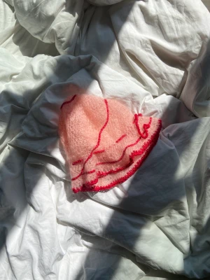 virkad mössa - Virkad hatt av mig!  Köper majoriteten av mina garn second hand, därför kan innehållet variera och är oftast inte specifierat. Denna har ett handvirkat rött ”band” trätt igenom hatten så att man kan knyta en rosett/spänna åt hur man själv önskar:)