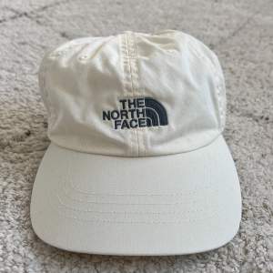 TNF keps i en sail/cream white färg. Tvättad så ser helt ny ut, onesize med justerbar strap på baksidan. Riktigt snygg färg och nyskick!