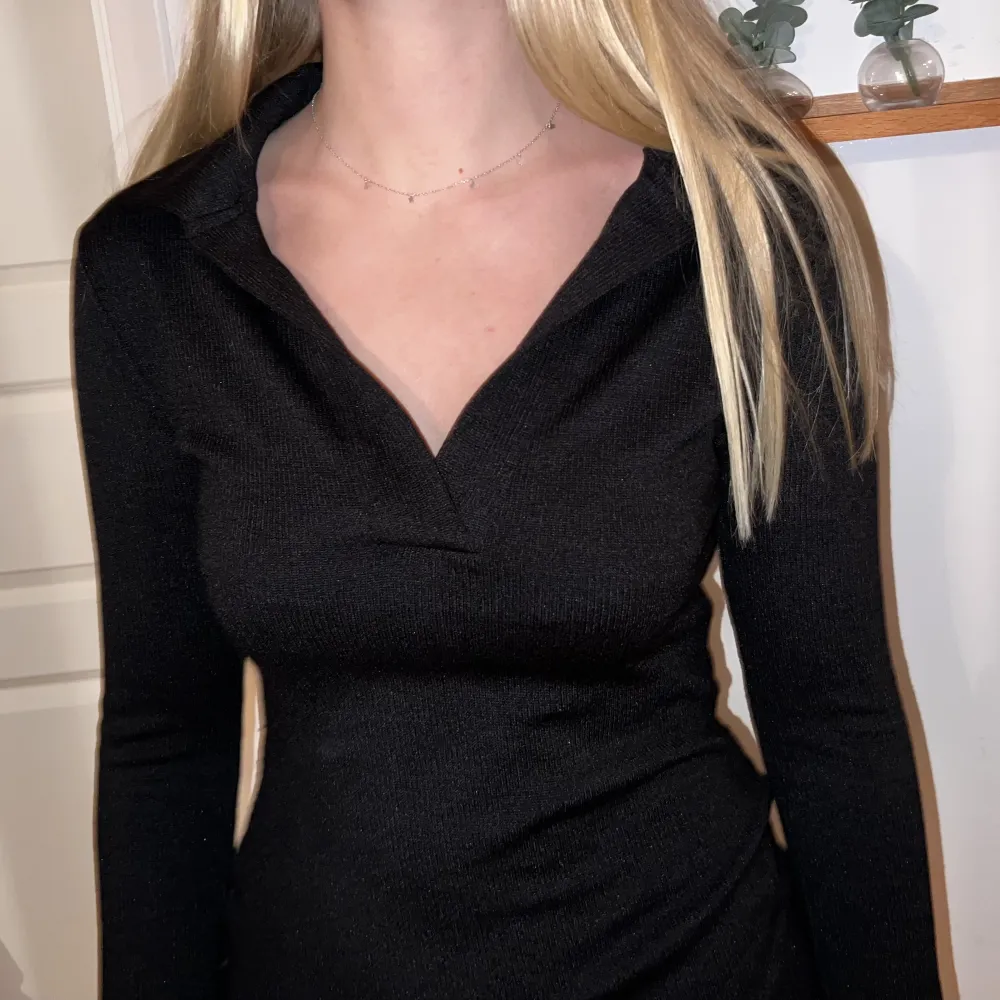 En svart långärmad klänning i lite stickat material med en urringning med ”krage” från Gina Tricot, långa ärmar med slits . Klänningar.