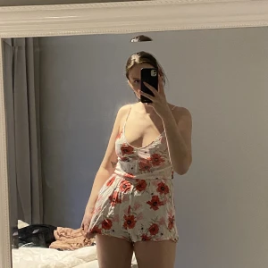 Playsuit med fickor - Vit playsuit med röda vallmoblommor, tunna axelband och fickor Passar S-M