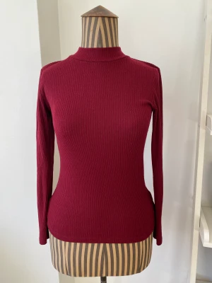 Polotopp från Uniqlo - Ribbad polotröja från Uniqlo. Härlig mörkröd färg. Tecken på användning men fortfarande bra skick. Storlek S men jag tycker den är liten.