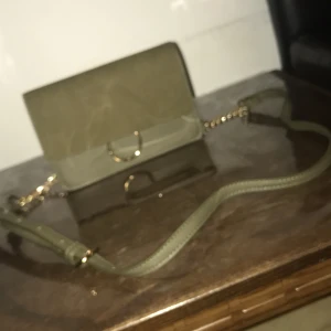 Väska - En fin mörkgrön väska med kedja från Åhléns. Köpte den för 500kr. Har använt den ett par gånger men annars har den inte kommit i använd så mycket. 