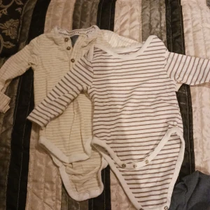 2 bodies barn - Från vänster: 1st vit/gul randig långärmad, 1st vit/brun randig långärmad. Storlek 62. Använt skick.