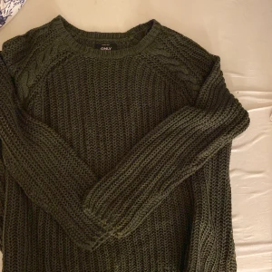 Militärgrön stickad  - En super fin militärgrön stickad tröja som har flätningar på varsin sida vid axeln. 