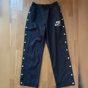 NIKE SPORTSWEAR byxa - Tryckknappar hela vägen. Två fickor fram. Resårmudd i midja. Mycket bra skick. 