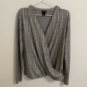 Festlig topp - Som ny, endast använd ett fåtal gånger. Perfekt för festliga tillfällen. Vacker grå/beige topp med lite guldskimmer i. 