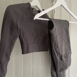 Amin set- XS - Aimn set. En ribbed seamless cropped longsleeve XS och tillhörande thights S. Försökte hitta vad färgen kallades på hemsidan men hittade inte, köpt för 2 år sedan. Använd ca 5 ggr men är nu för litet. Väldigt fräscht skick. Ca 1100kr nypris. Mörkgrå.